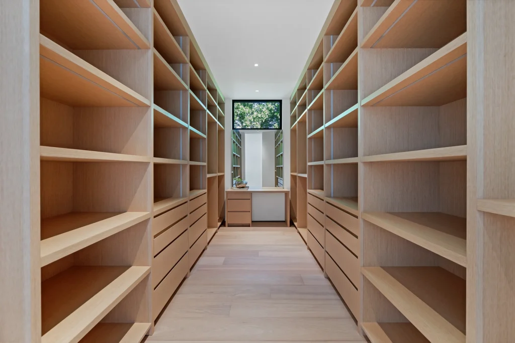 Spacious walk-in closet with custom wooden shelves in a Miami waterfront property for sale.