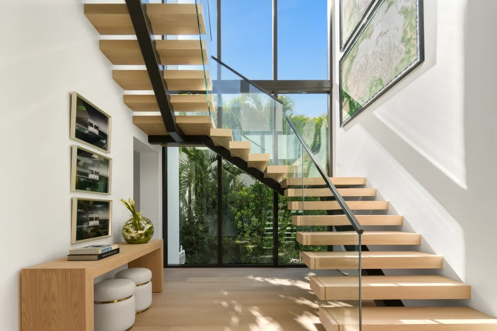 Modern floating staircase with glass railing in a waterfront property for sale.